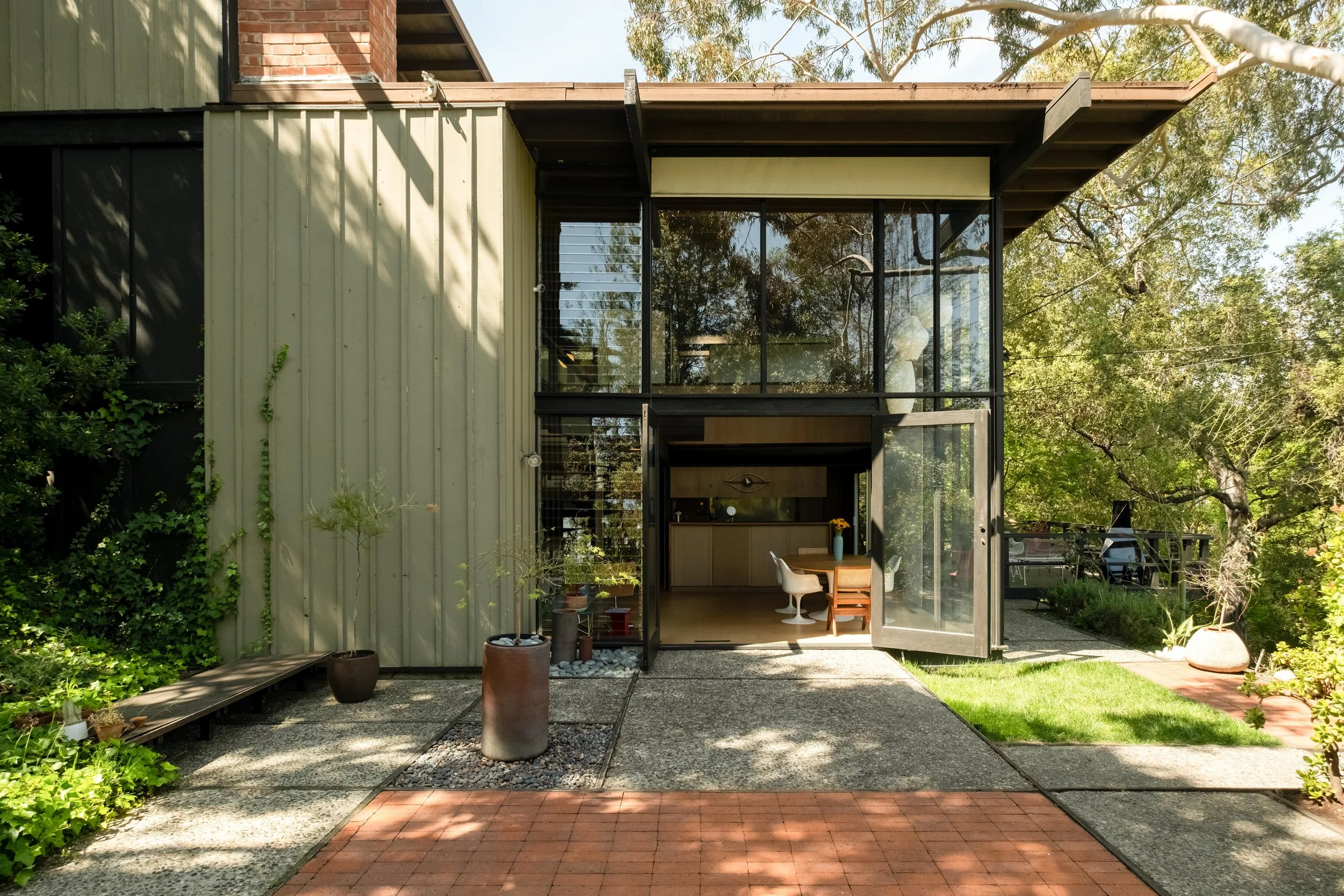 Entrance framed by glass and hillside planting